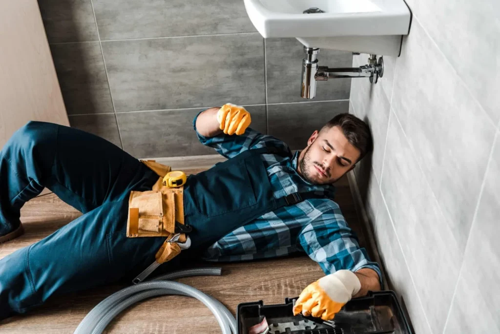 About Company - Bearded Handyman Lying On Floor Near Toolbox In Bathroom - Dreams Care Technical Services LLC